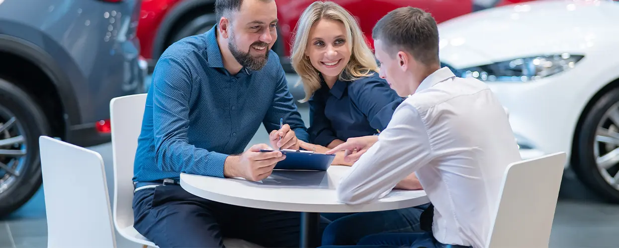 three people in car showroom discussing something