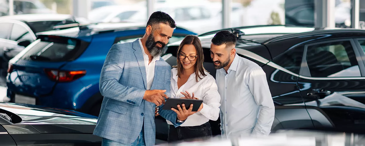 Car salesman showing customers something on a tablet