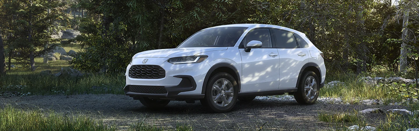 Side viewe of a parked white 2026 Honda HR-V in a forest