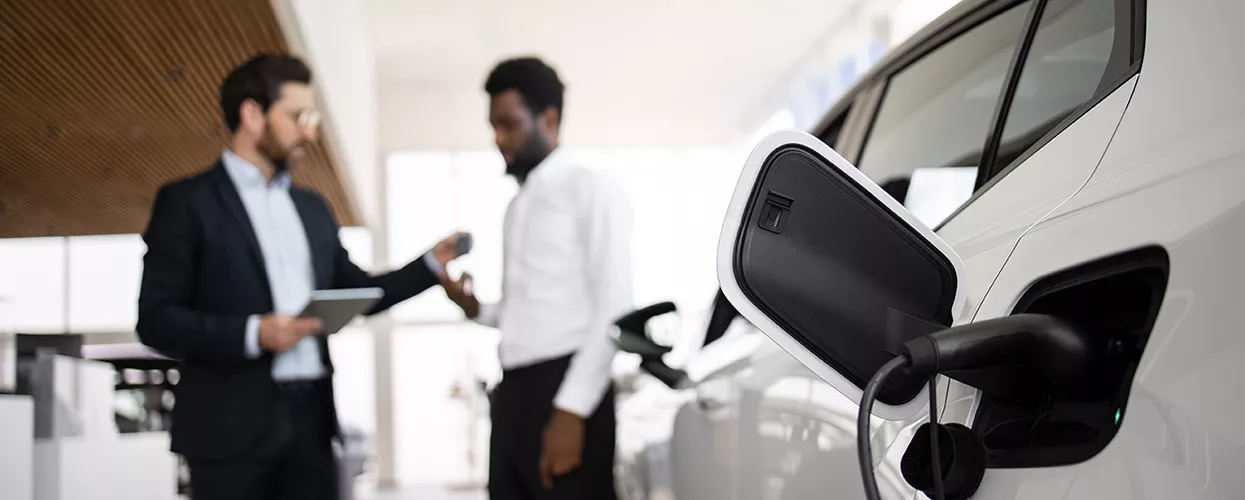 Car salesman and cutomer talking in front of an electric vehicle
