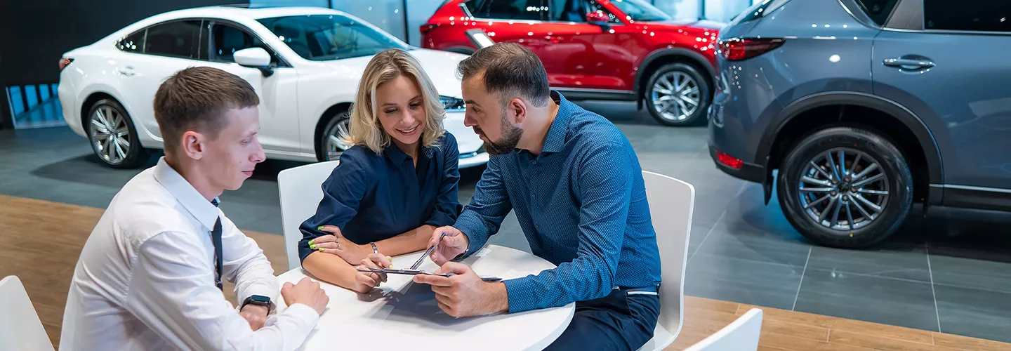 Three people sitting down at a table together at a car dealership
