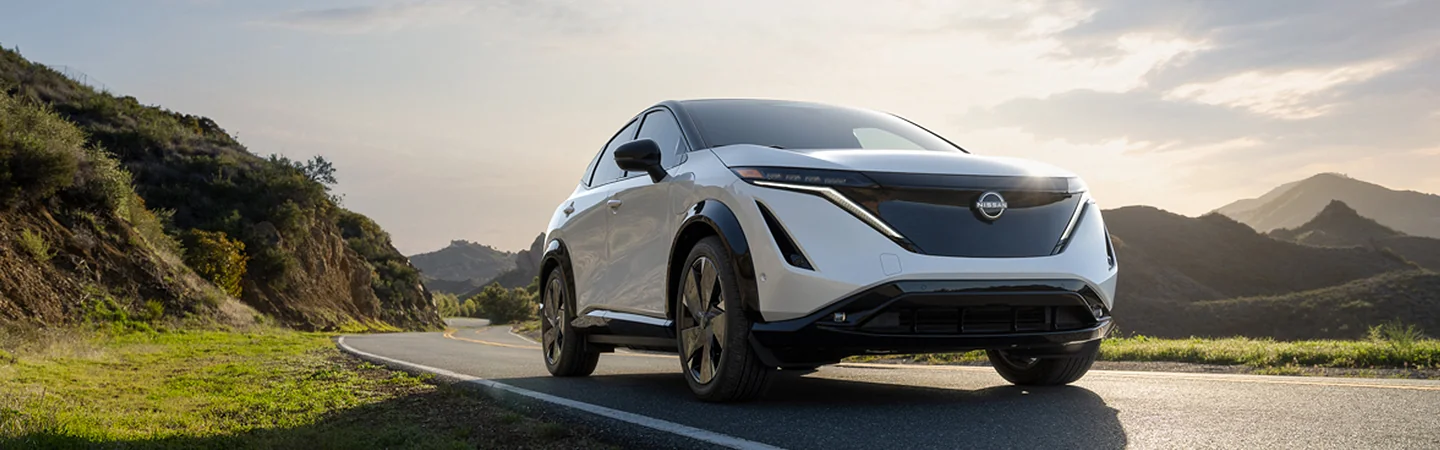 a white 2025 Nissan ARIYA ENGAGE driving on a country road