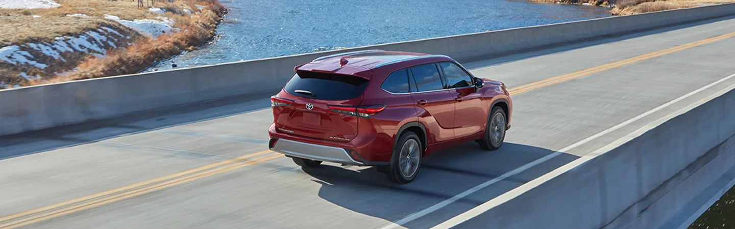 red 2025 Toyota Highlander Platinum rear view crossing a bridge