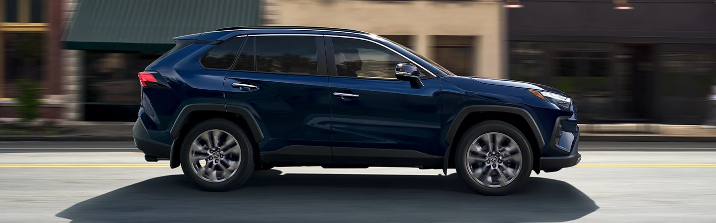 passenger side view in motion 2025 Toyota RAV4 LE drving in a city