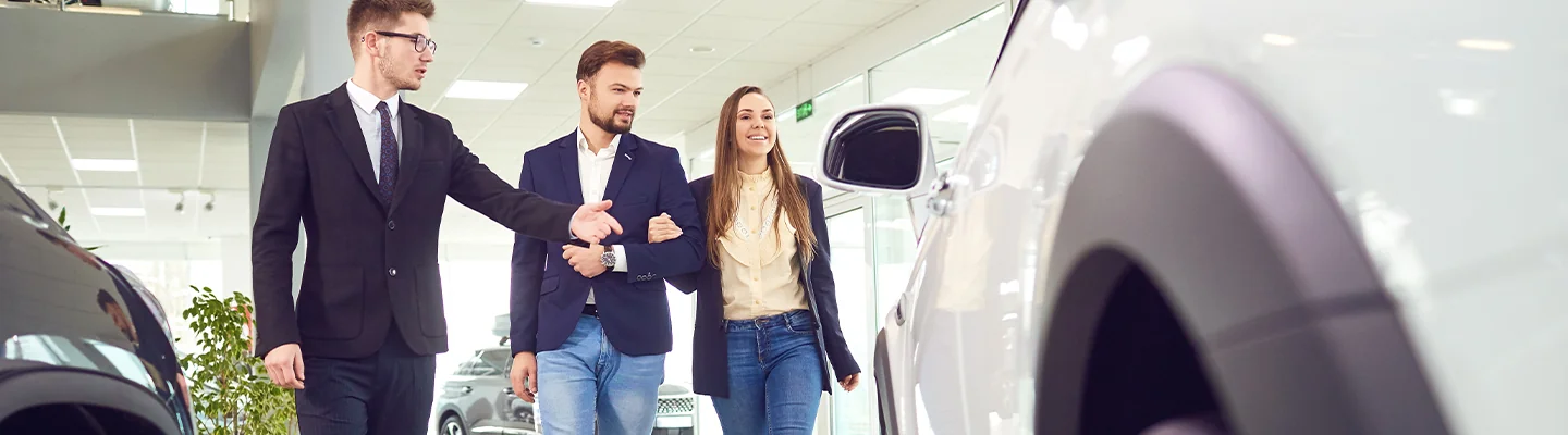 two people discussing a car's features in the showroom with a salesperson