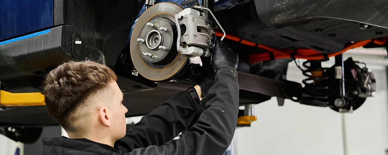 Service technician working on the brakes of a Honda vehicle at a dealership
