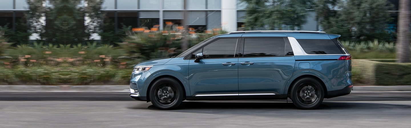 blue Kia Carnival driving
