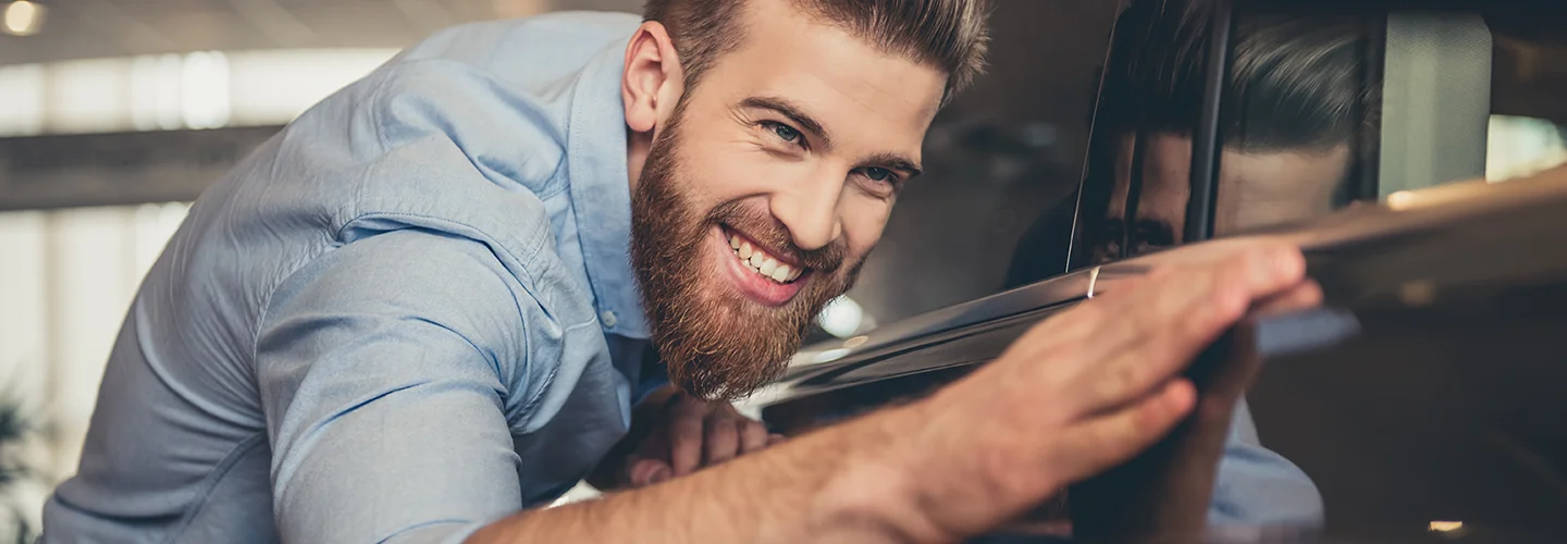 a person smiling looking at a exterior curve of a car