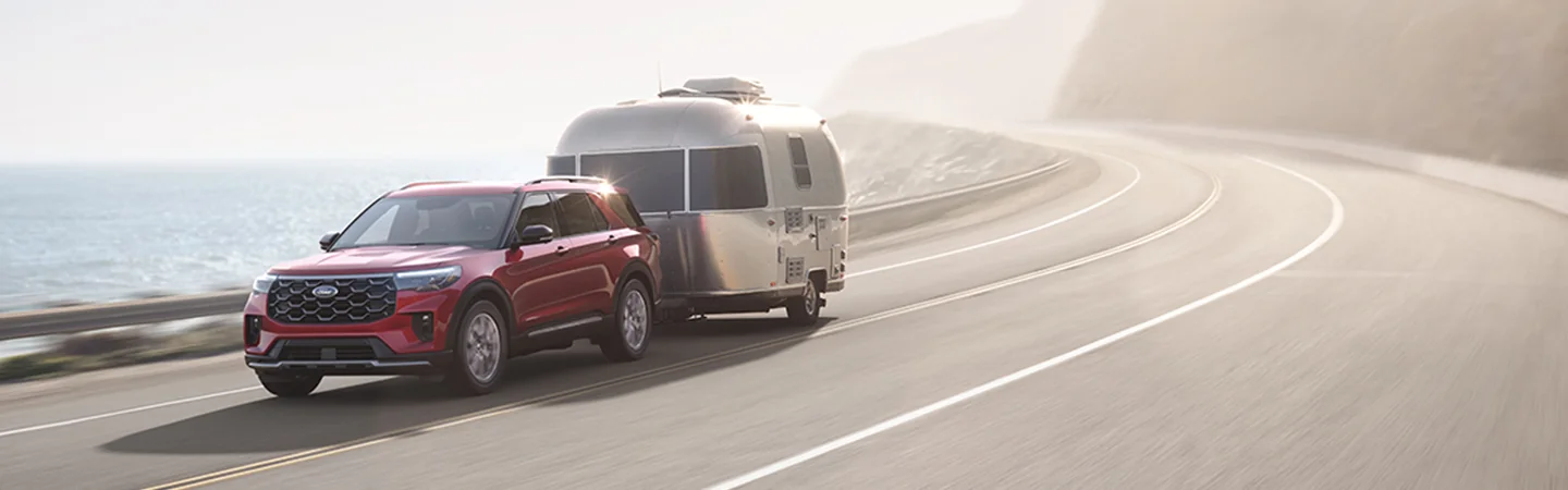 A red 2025 Ford Explorer pulling a trialer down a road