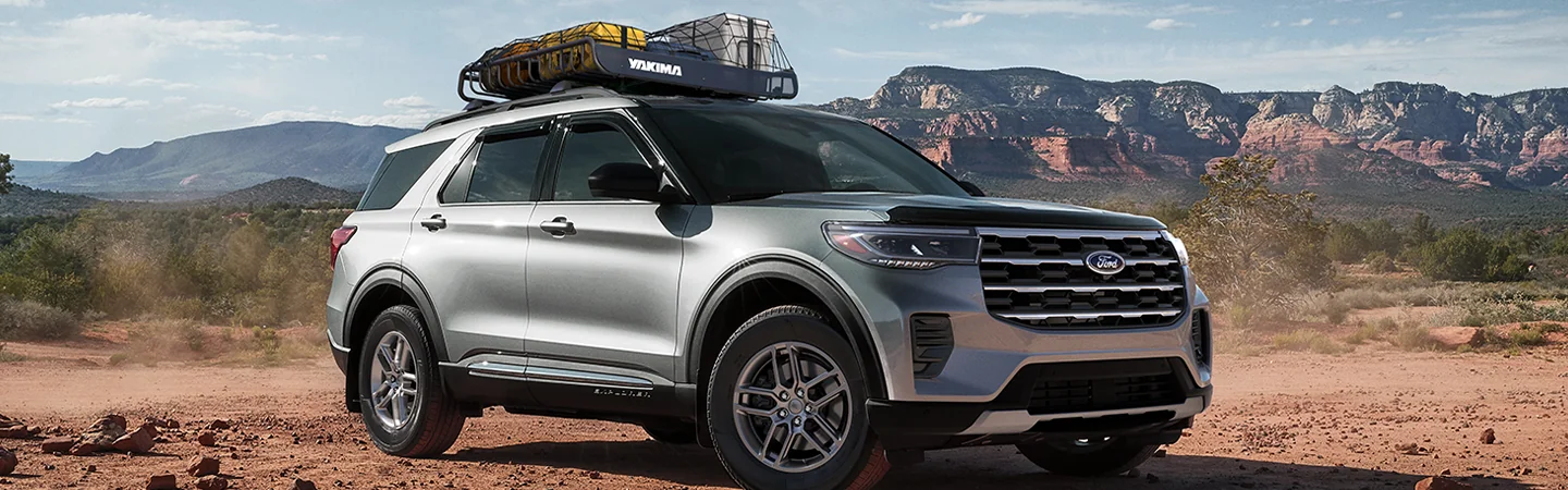 Front side view of a parked gary 2025 Ford Explorer in the desret with mountains in the background