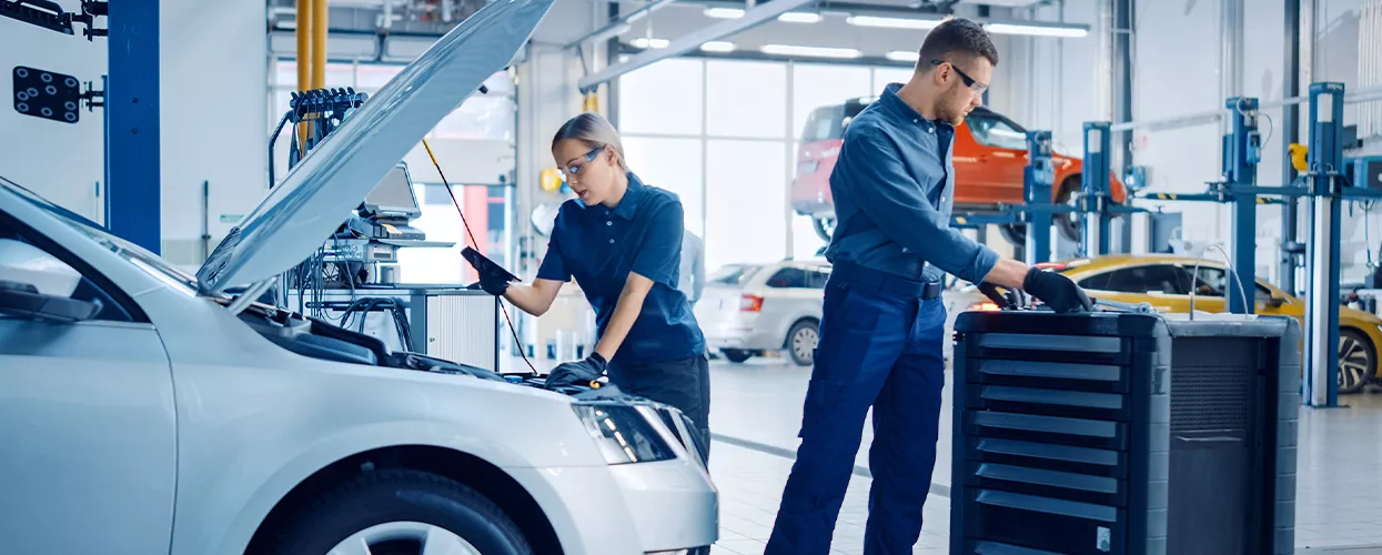 Two service mechanics working on a vehicle with its hood up
