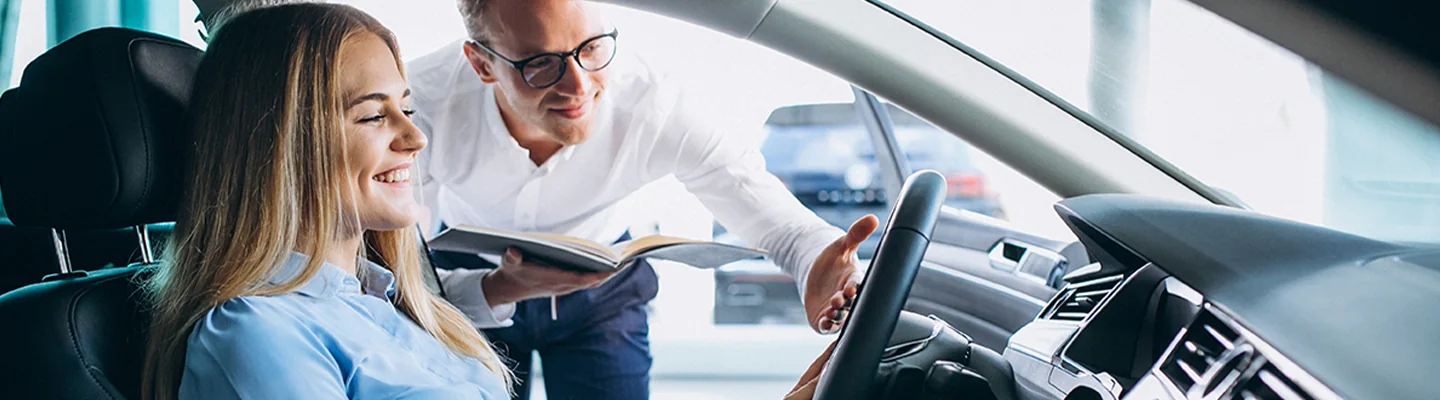 smiling person in car with another person in the door showing the car