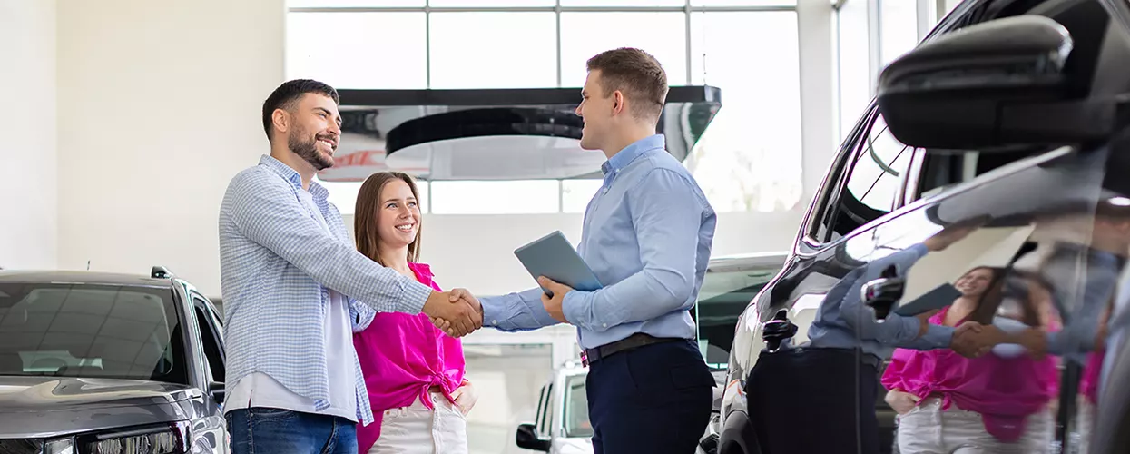 Car salesman shaking hands with a couple looking for a new vehicle