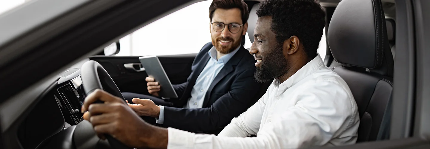 Customer sitting in a car with a sales person telling him about the car
