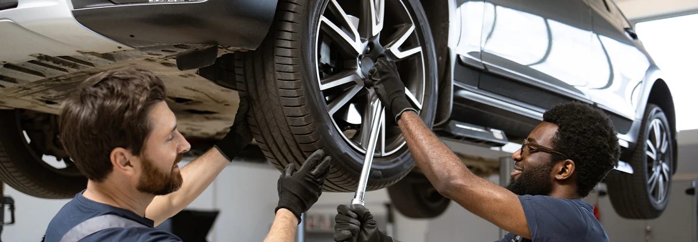 two auto mechanics working in car on lift in service bay