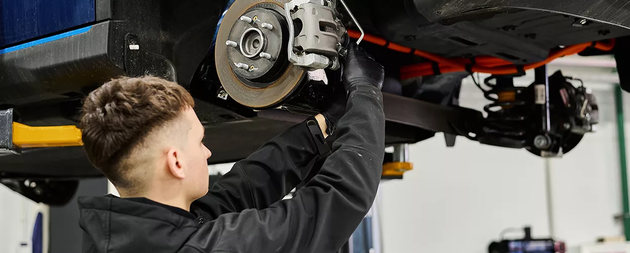 Technician performing a Nissan brake service in a dealership bay