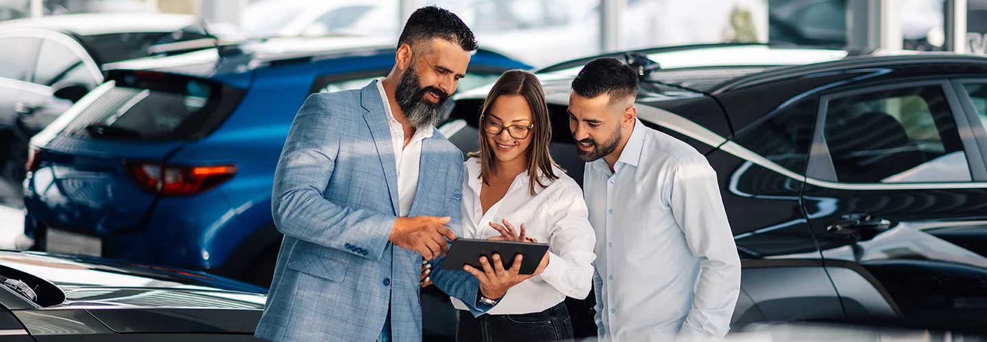 Sales person showing customers information about a new car they are looking at
