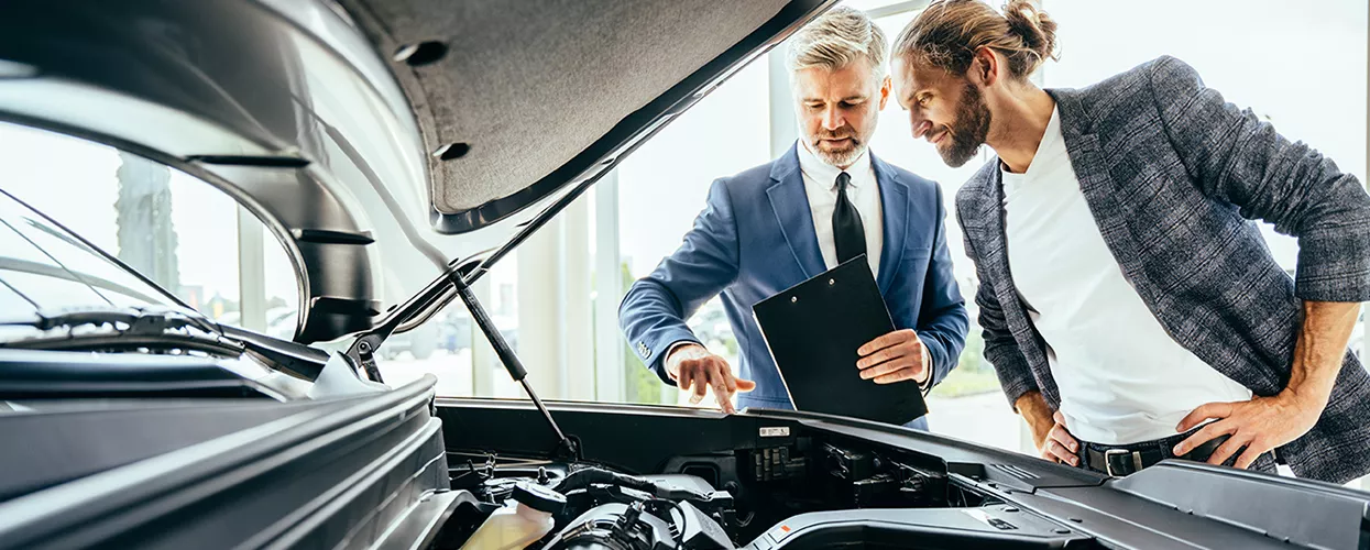Car salesman and customer looking under the hood of a volkswagen