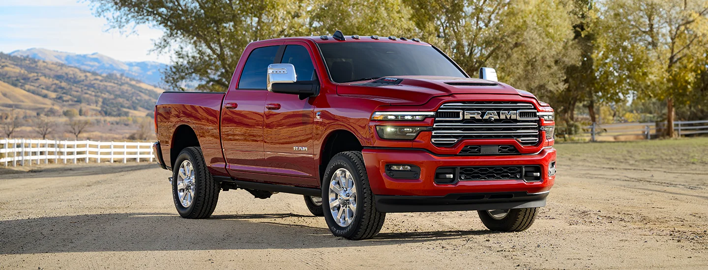 Front side view of a red 2025 RAM 2500 parked on a farm