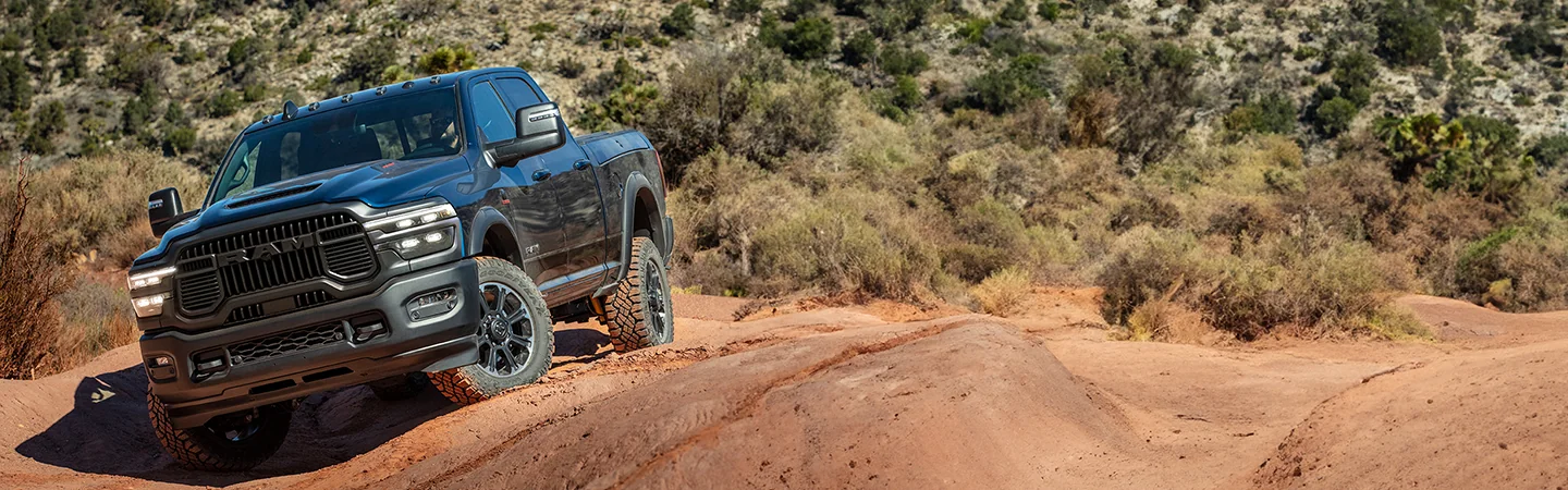 A black 2025 RAM 2500 driving over some sand dunes