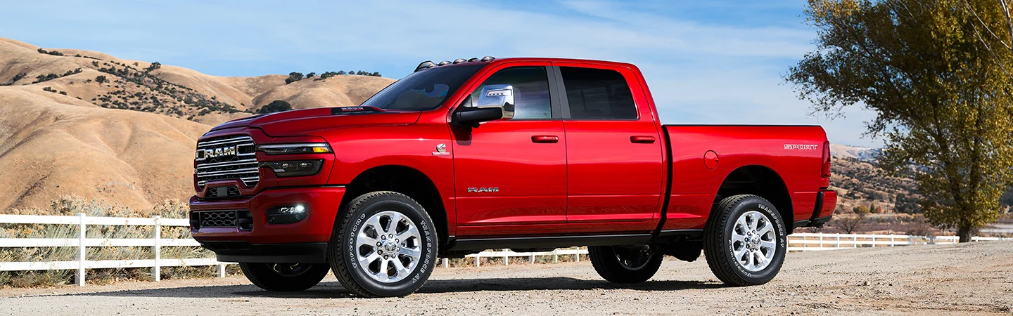 Side view of a red 2025 RAM 2500 with sand dunes in the background