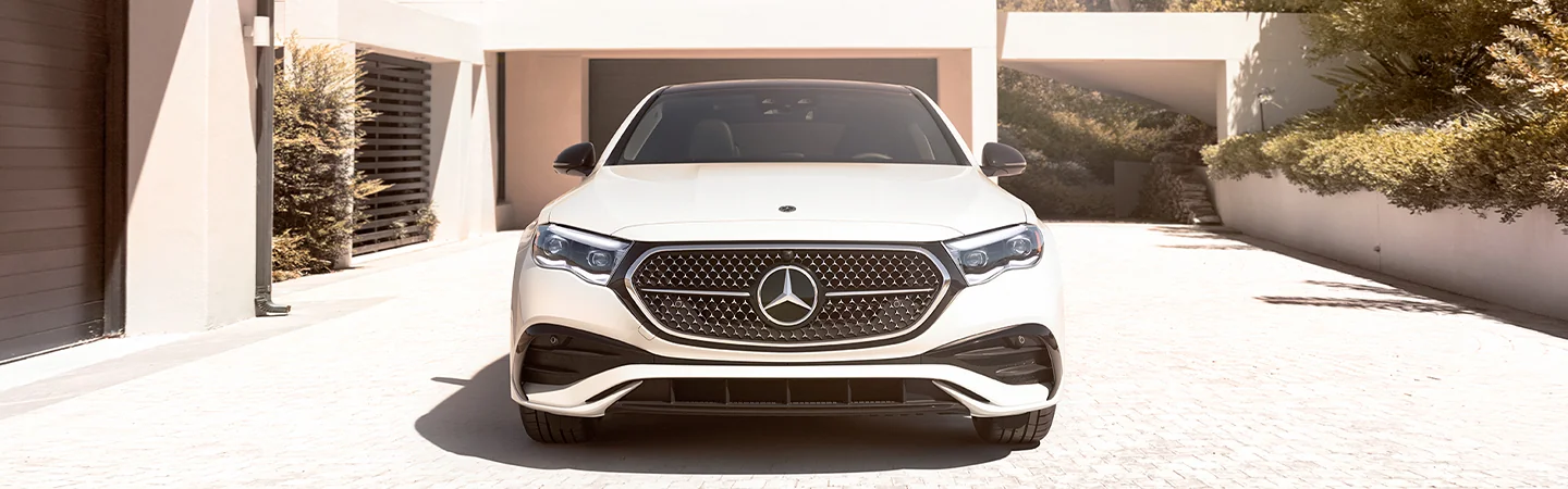 Front view of the 2025 Mercedes-Benz E-Class parked in front of a building in the sun