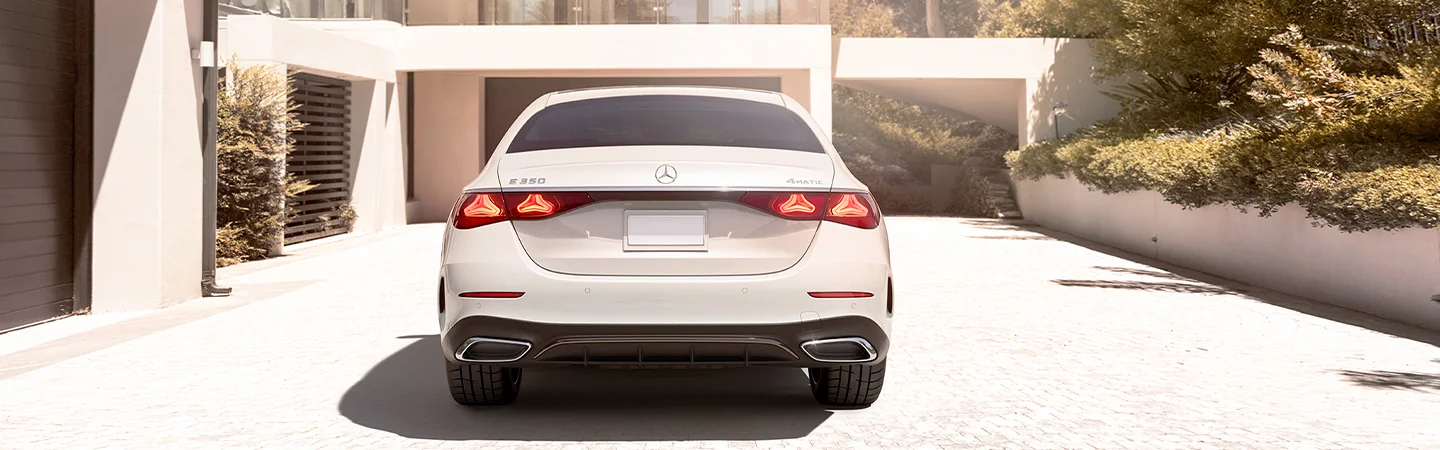Rear view of the 2025 Mercedes-Benz E-Class parked in front of a building in the sun