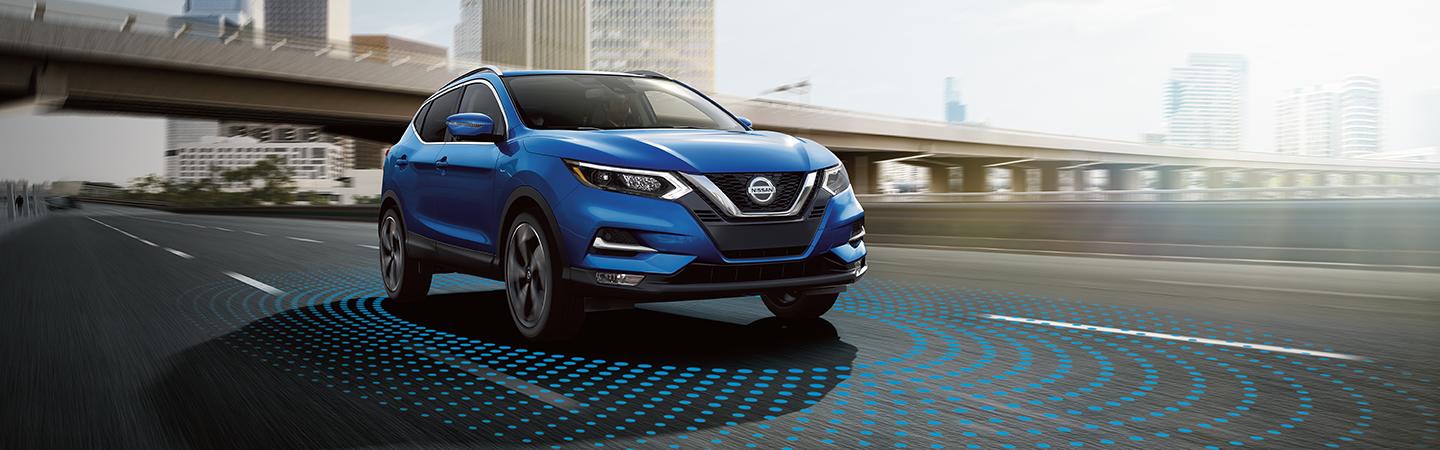 Blue 2021 Nissan Rogue driving in the city