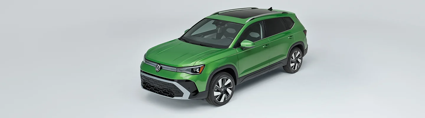 A green 2025 Volkswagen Taos in a white show room.