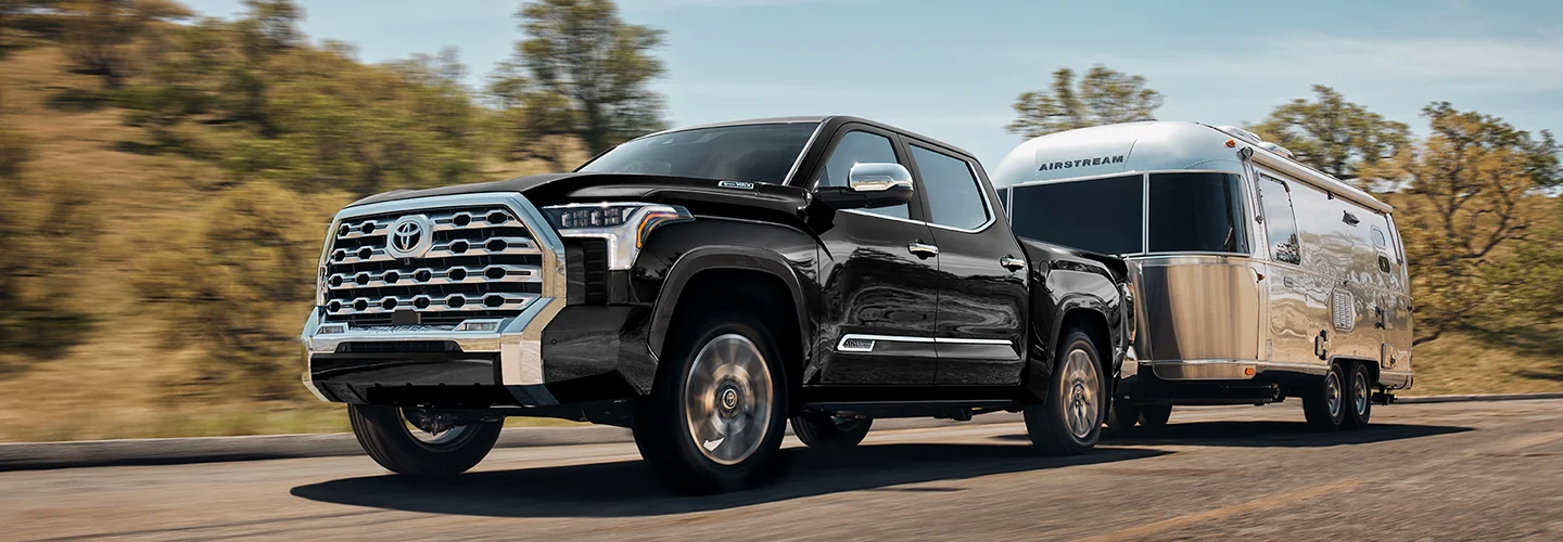 A Toyota Tundra towing a trailer on a road, showcasing its powerful performance and utility.