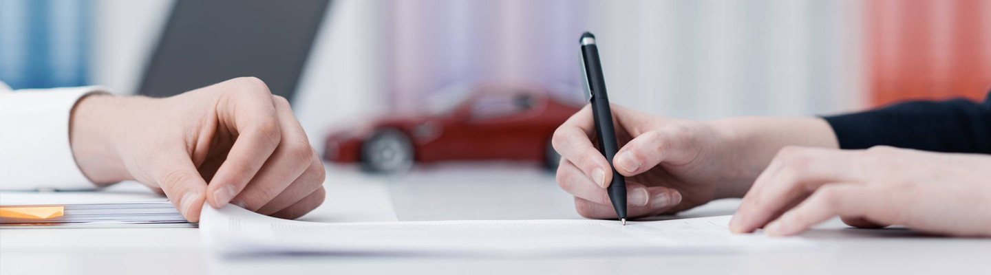 Close up view of a customer signing a contract in a dealership