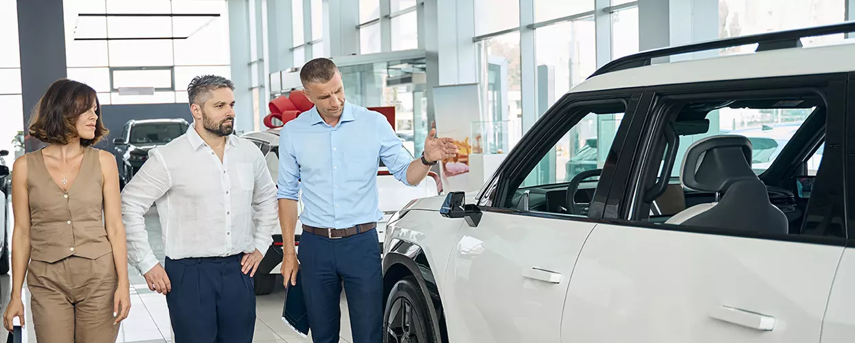 Car salesman showing two people a new vehicle