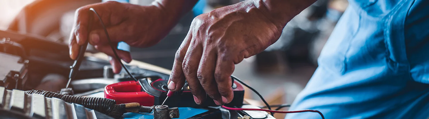 auto mechanic working on a car electric system testing voltages