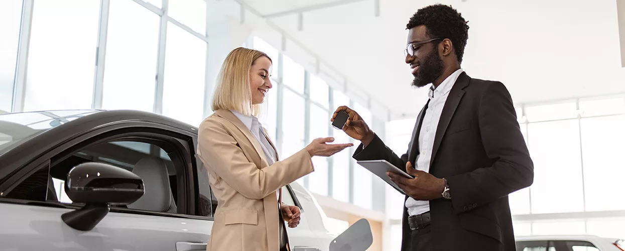 Car salesman handing a customer a new set of car keys