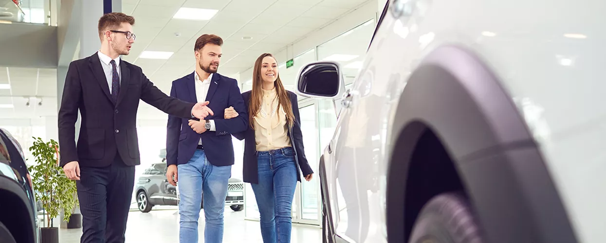 Sales person showing customers a new Nissan car in the showroom