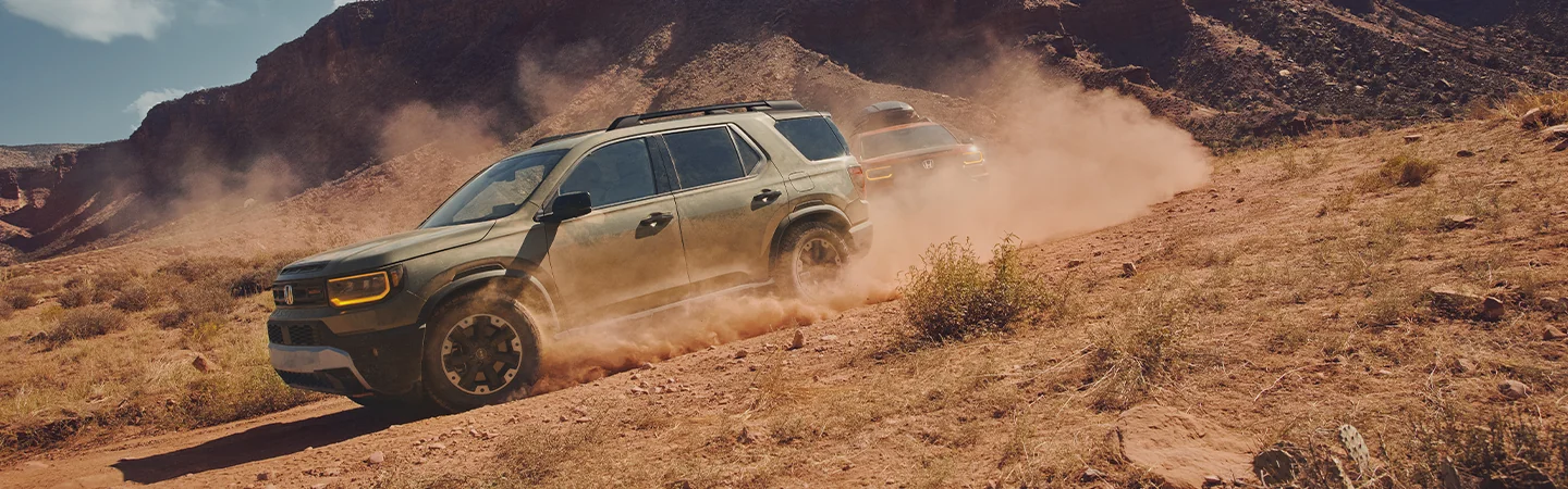 2 2026 Honda Passport RTLs turning a corner offroad and picking up dust