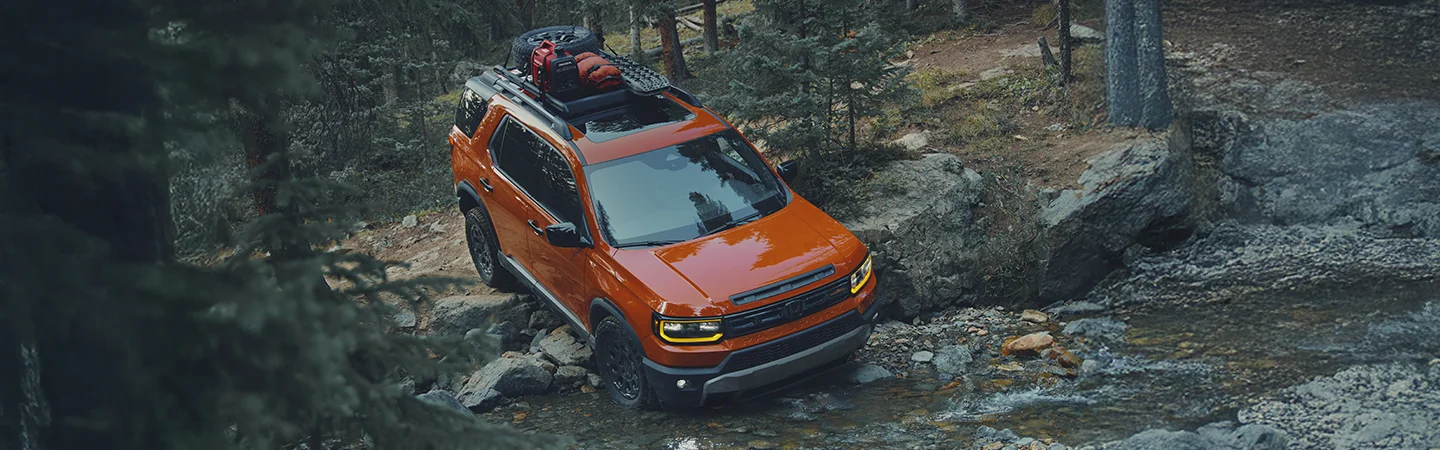 top view of a 2026 Honda Passport RTL climbing a rocky incline with camping gear on rack above