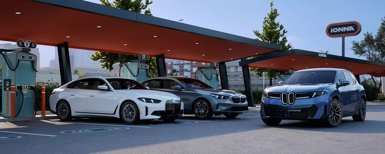 BMW EV and Plug-In information in BMW EV and Plug-In information in 2 BMWs parked under a car port with a BMW SUV driving by