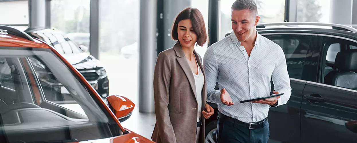 Car shoppers reviewing a new SUV with a dealership representative in a modern automotive showroom