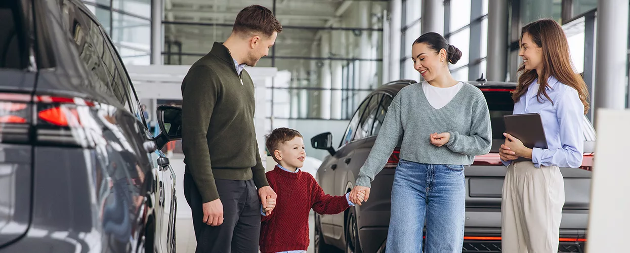 Family of three speaking with car salesperson at a dealership