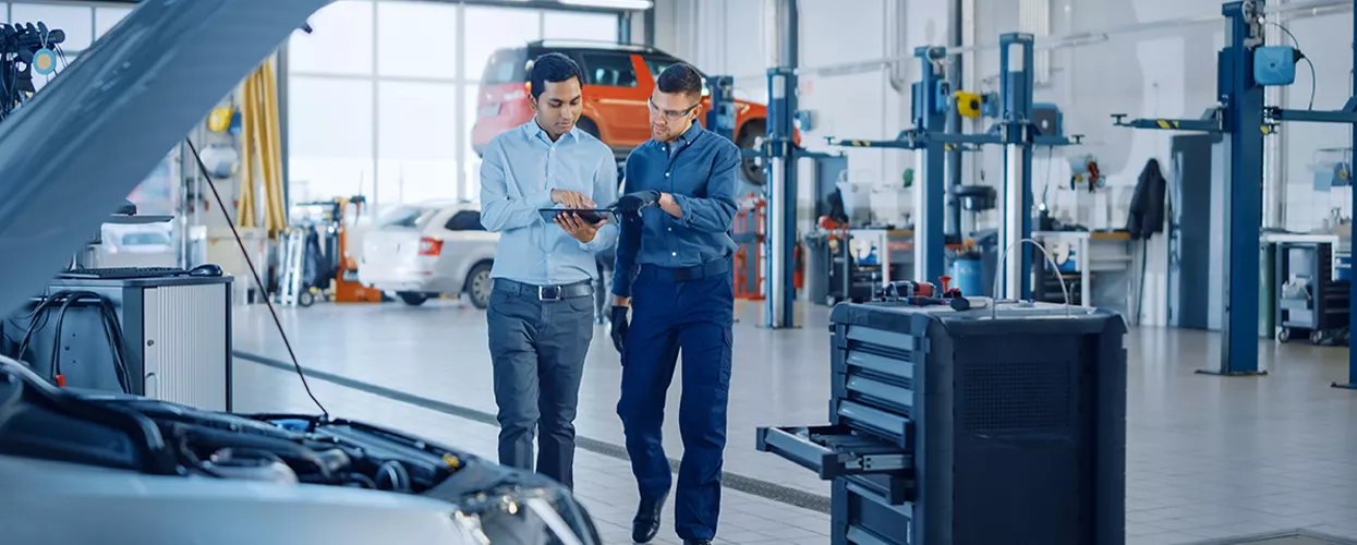 Service mechanic and salesamn holding a tablet in a service bay