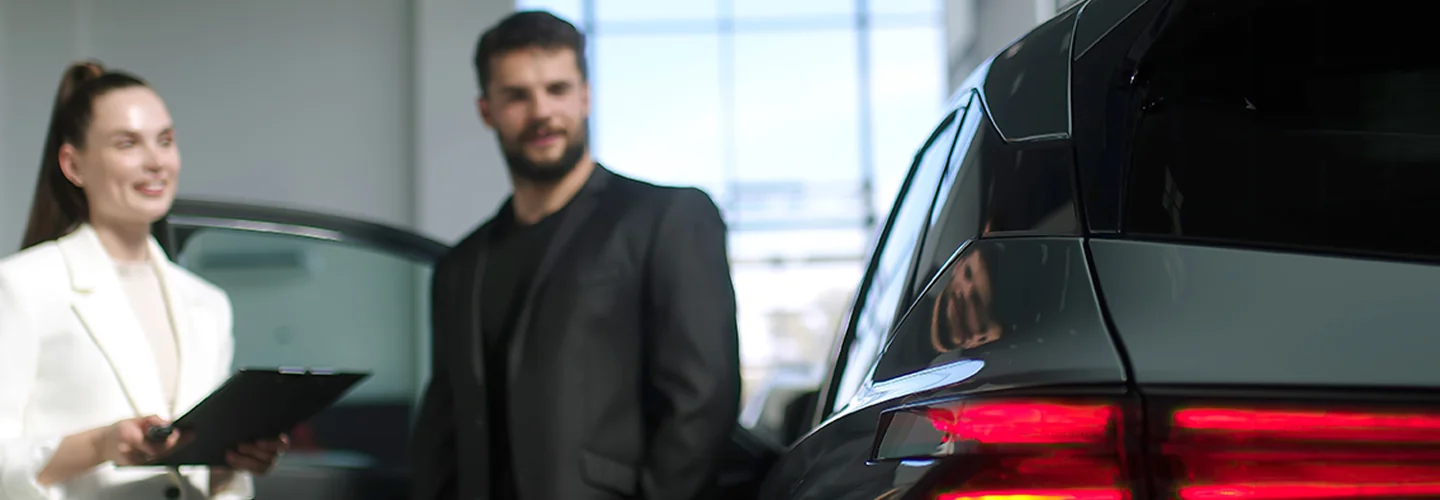 two people looking over a car in the showroom