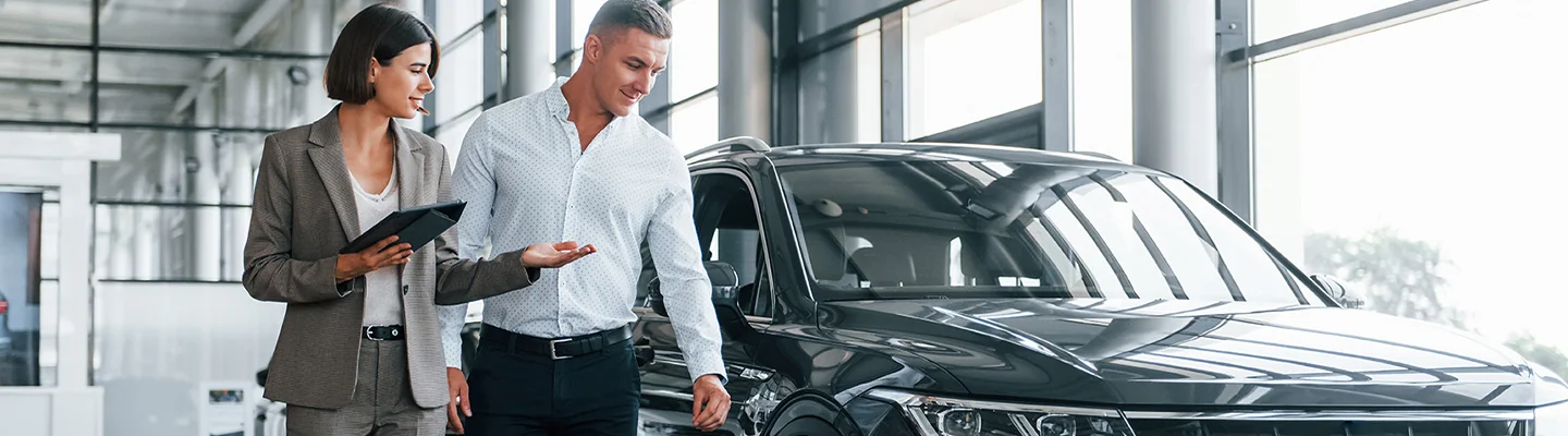 Two people looking at a Kia vehicle