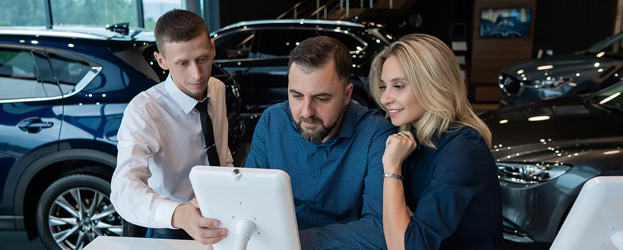 BMW of Sarasota is your Gulf Coast Luxury and Performance Hub in Car buyers reviewing vehicle features and pricing with a dealership representative in an automotive showroom
