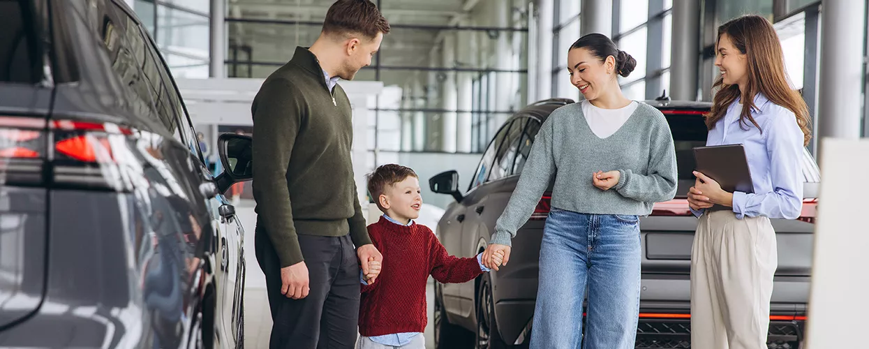 Family talking to a car saleswoman at a car dealership