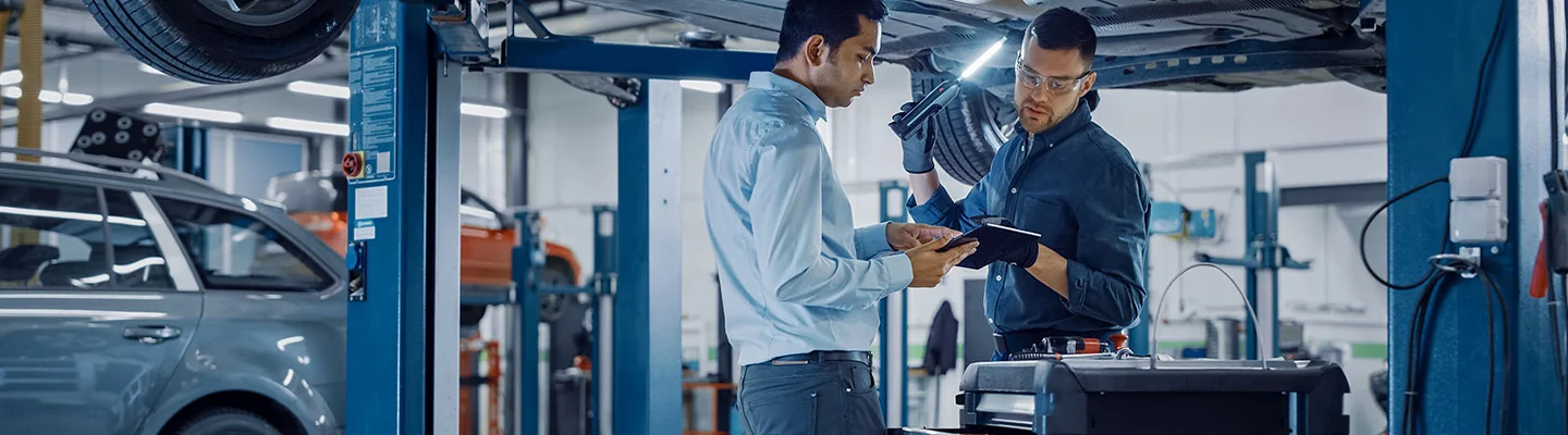 auto mechanics discussing a service job with car on lift