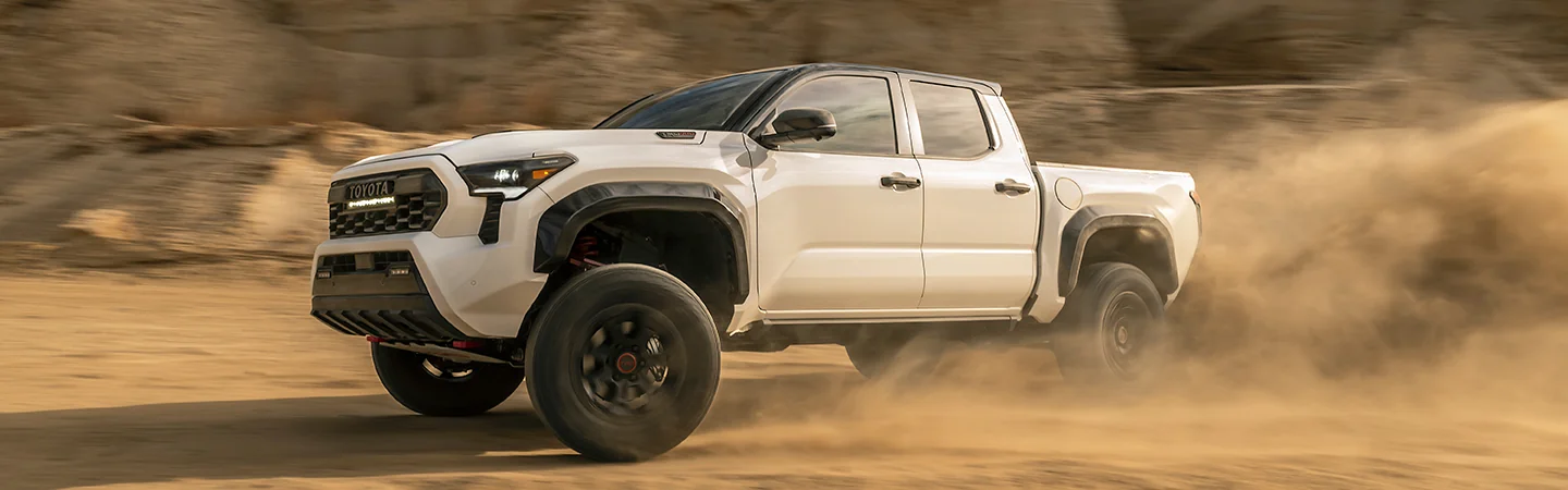 White 2025 Toyota Tacoma driving in the dirt