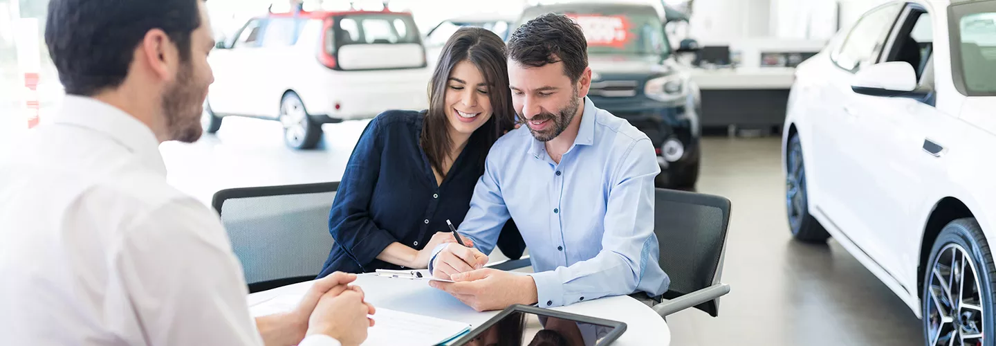 Car salesman talking with a couple and signing a paper