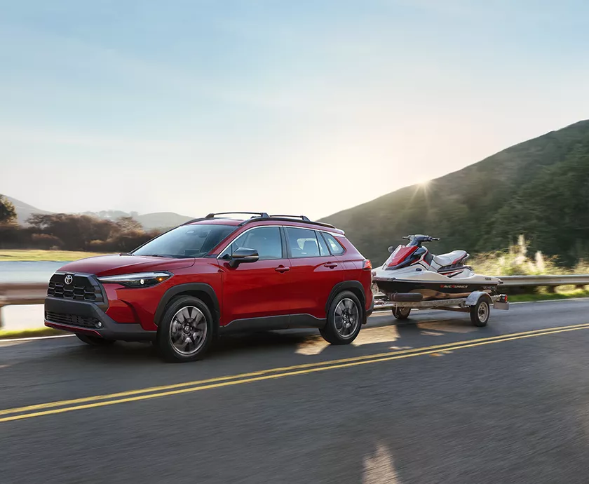 Side view of a red 2026 Toyota Corolla Cross pulling a jetski in Viera, FL