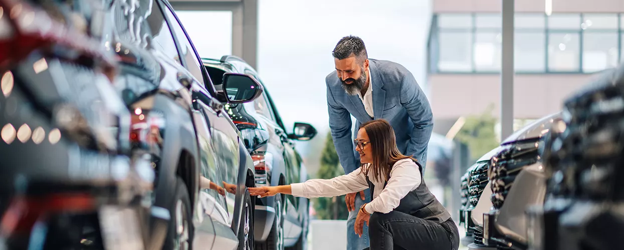 Car salesman showing a customer a new vehicle at a car dealership
